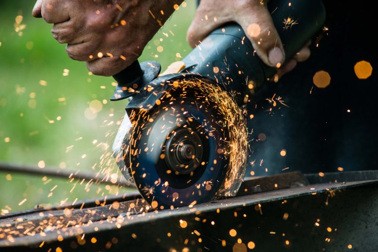 Closeup of worker using a grinder on a metal plate